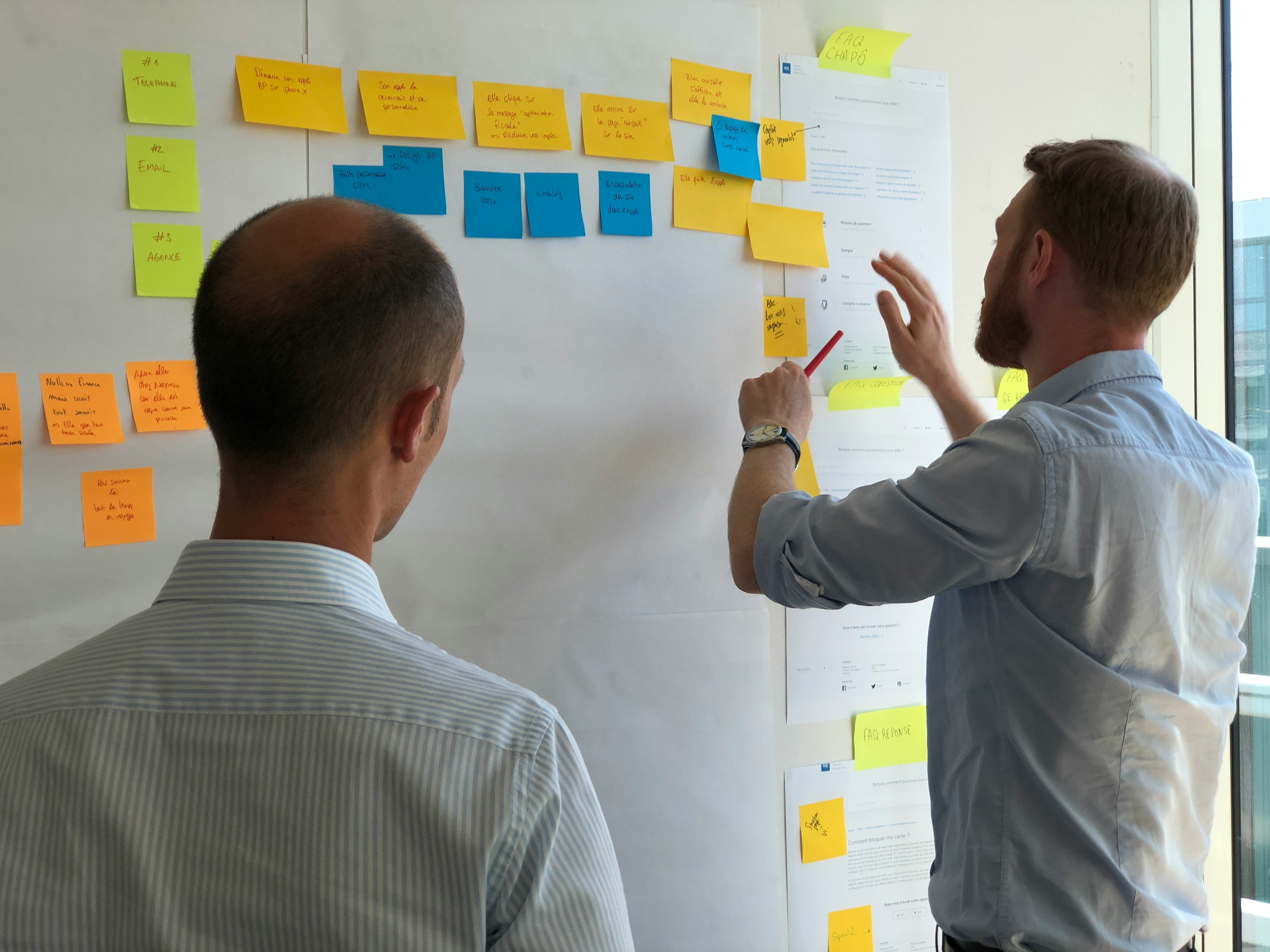 Two gentlemen developing a process flow using sticky notes.